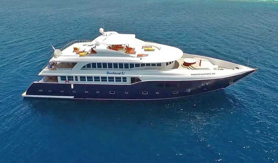 An aerial view of the 138-foot Blue Force One dive yacht at rest in the waters of  a Maldives atoll