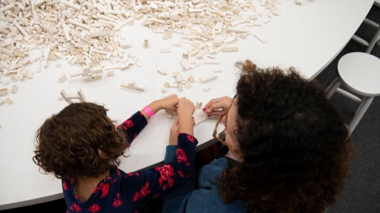 Uma pessoa adulta e uma criança brincam com LEGOS brancos.