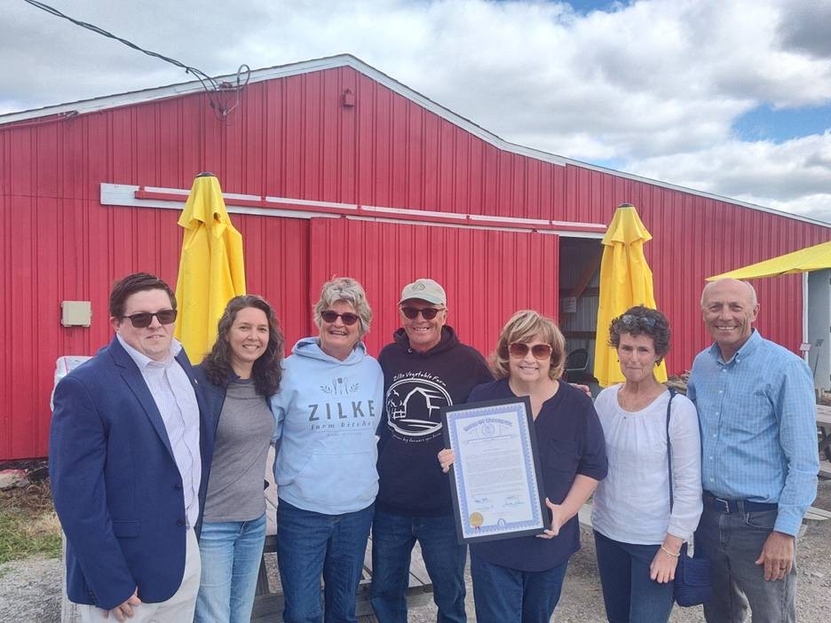 Michigan state Representative Reggie Miller and Tom and Vicki Zilke with friends standing for a photo outside of Zilke Vegetable Farm stand. Representative Miller is holding a framed certificate for the Zilke's retirement. Michigan state Representative Reggie Miller and Tom and Vicki Zilke with friends standing for a photo outside of Zilke Vegetable Farm stand. Representative Miller is holding a framed certificate for the Zilke's retirement.