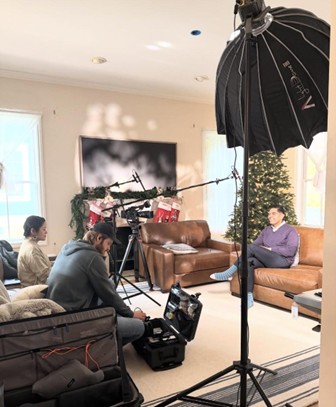 Democratic Leader Ranjeev Puri being interviewed on a couch in a living room space. Democratic Leader Ranjeev Puri being interviewed on a couch in a living room space.
