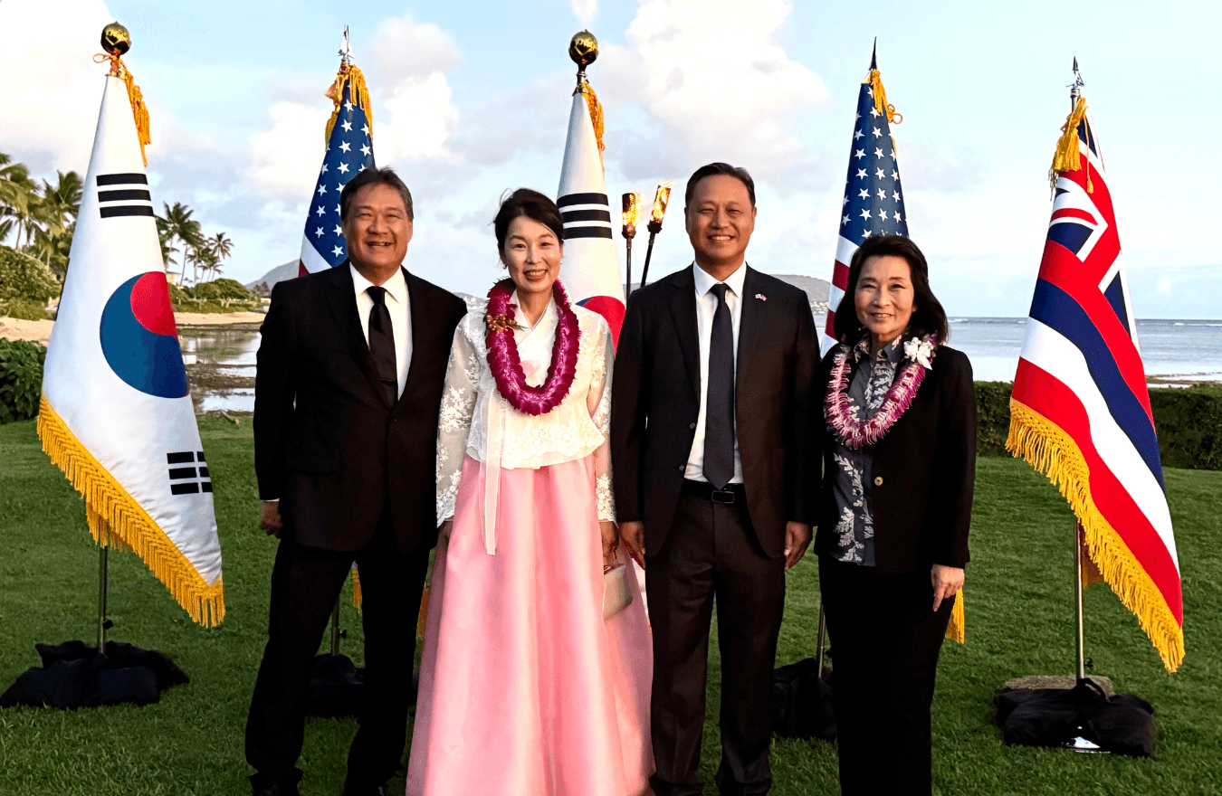 Lt. Gov. Sylvia Luke and group smiling for a photo outside in front of U.S., Hawaiian, and Korean flags. 