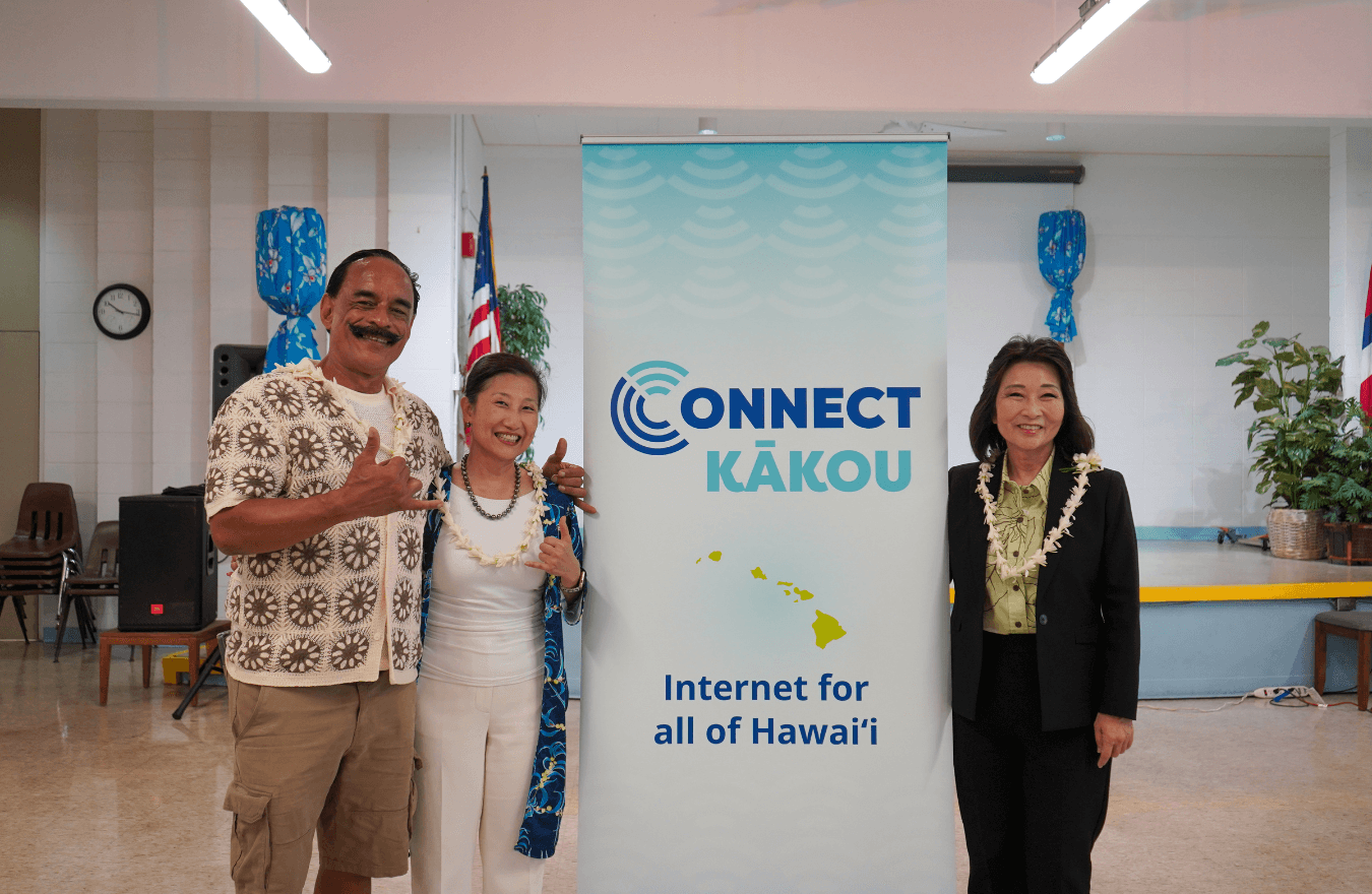 Lt. Gov. Sylvia Luke and group smiling for a group photo in front of a banner. 