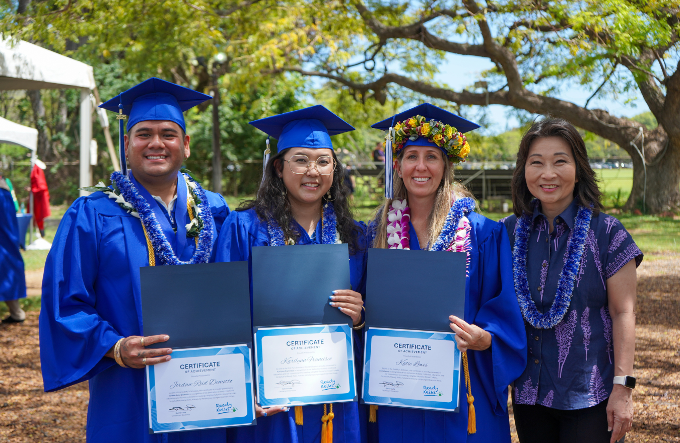 Lt. Gov. Sylvia Luke smiling for a group photo with graduates dressed in caps and gowns while holding certificates. 