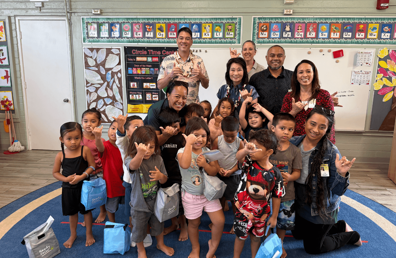 Lt. Gov. Sylvia Luke with legislator, teachers, and pre–k students smiling and holding up shakas in a Ready Keiki preschool classroom in North Shore, Oahu. 