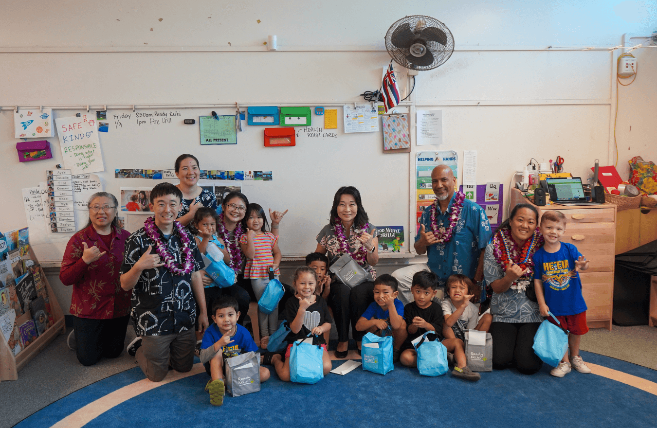 Lt. Gov. Sylvia Luke, teachers, and pre-k students smiling and holding up shakas in a Ready Keiki preschool classroom in Kāneʻohe, Oʻahu. 