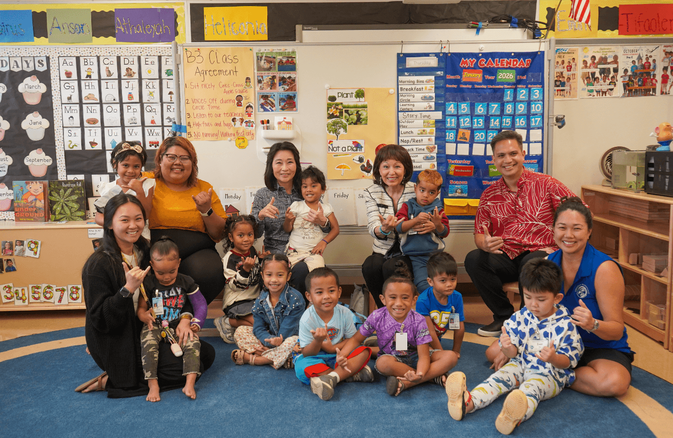 Lt. Gov. Sylvia Luke, legislators, teachers, and pre-k students smiling and holding up shakas in a Ready Keiki preschool classroom in Kalihi, Oʻahu. 