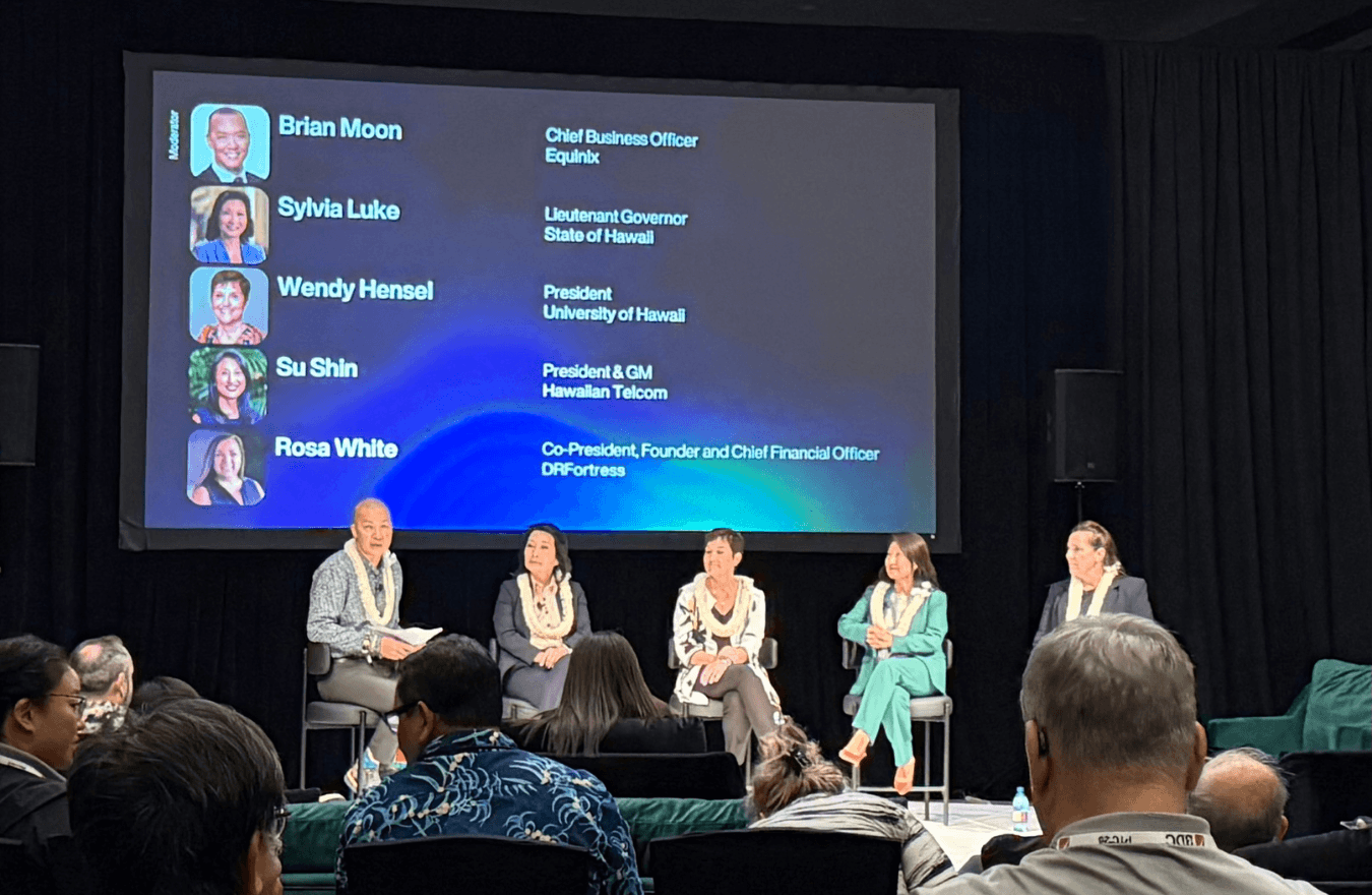 Lt. Gov. Sylvia Luke and group sitting on chairs on a stage in front of an audience. 