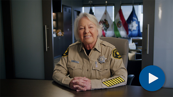A person taking a breathalizer test to see alcohal level. shows a car in the back with a machine being held with blue sticker with yellow xl type.