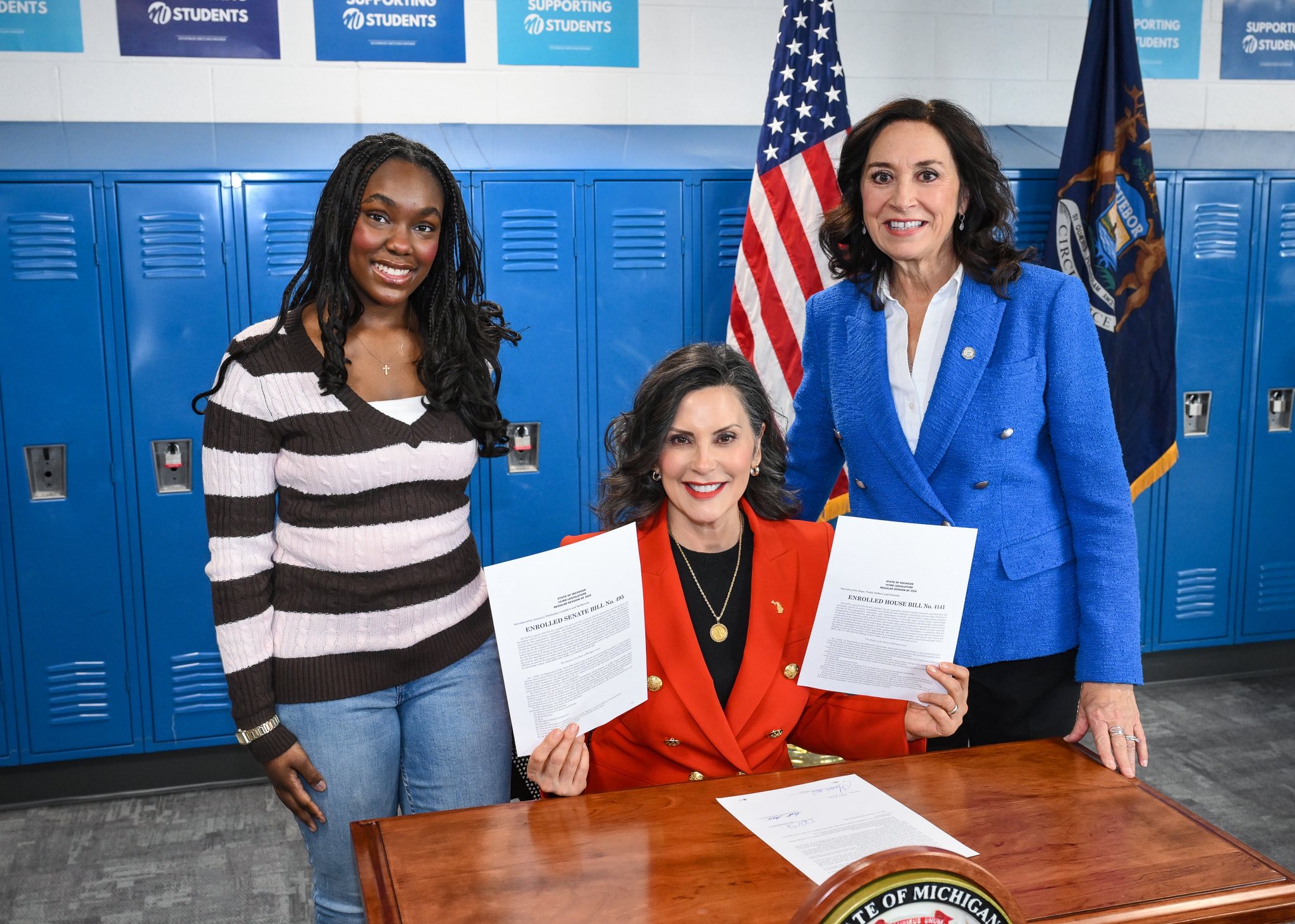 Michigan State Representative Angela Witwer, Governor Gretchen Whitmer and Waverly High School student Callan Maxwell pose for a picture at the bill signing of school cell phone legislation in front of a row of school lockers. Michigan State Representative Angela Witwer, Governor Gretchen Whitmer and Waverly High School student Callan Maxwell pose for a picture at the bill signing of school cell phone legislation in front of a row of school lockers.