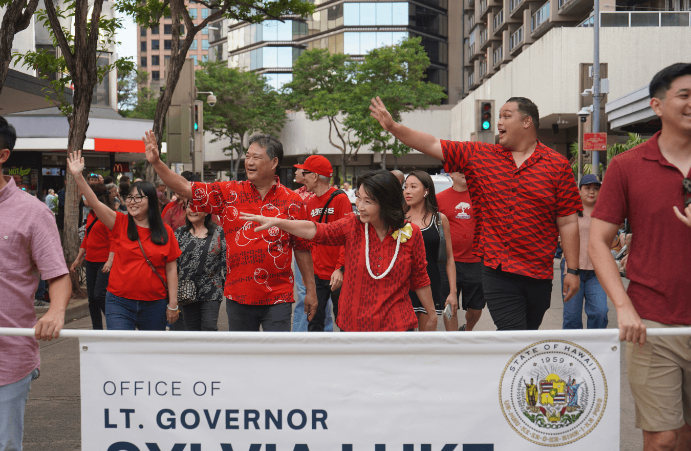 Lt. Gov. Sylvia Luke and group smiling and waving outdoors during a parade. 