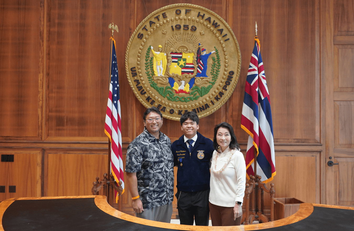 Lt. Gov. Sylvia Luke and group smiling for a group photo in front of the Hawaiʻi State Seal. 