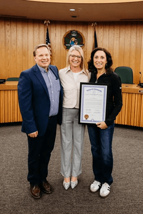 Michigan state Representative Angela Witwer presenting a framed tribute certificate to Connie Sobie, alongside Chairman Jim Mott. Michigan state Representative Angela Witwer presenting a framed tribute certificate to Connie Sobie, alongside Chairman Jim Mott.