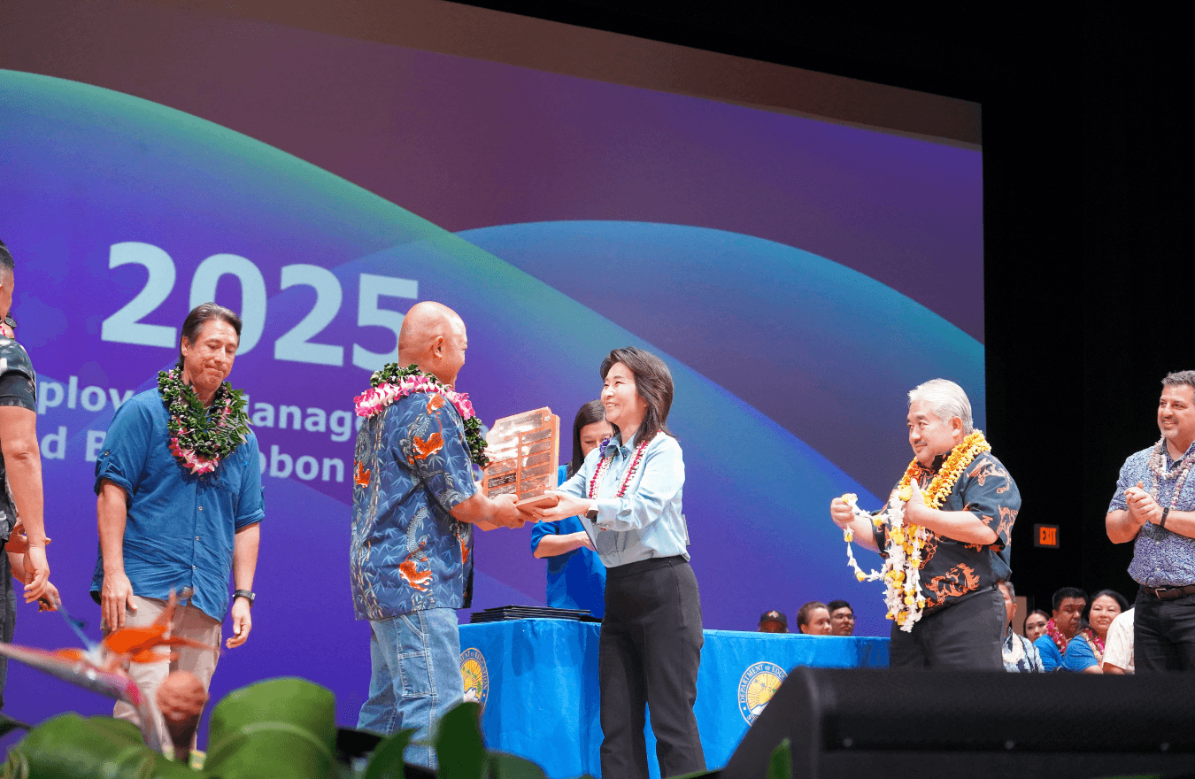 Lt. Gov. Sylvia Luke smiling while handing a plaque to a man. 