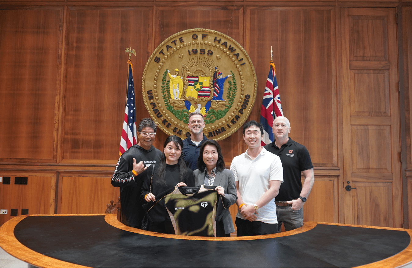 Lt. Gov. Sylvia Luke and group smiling for a group photo in front of the Hawaiʻi State Seal. 