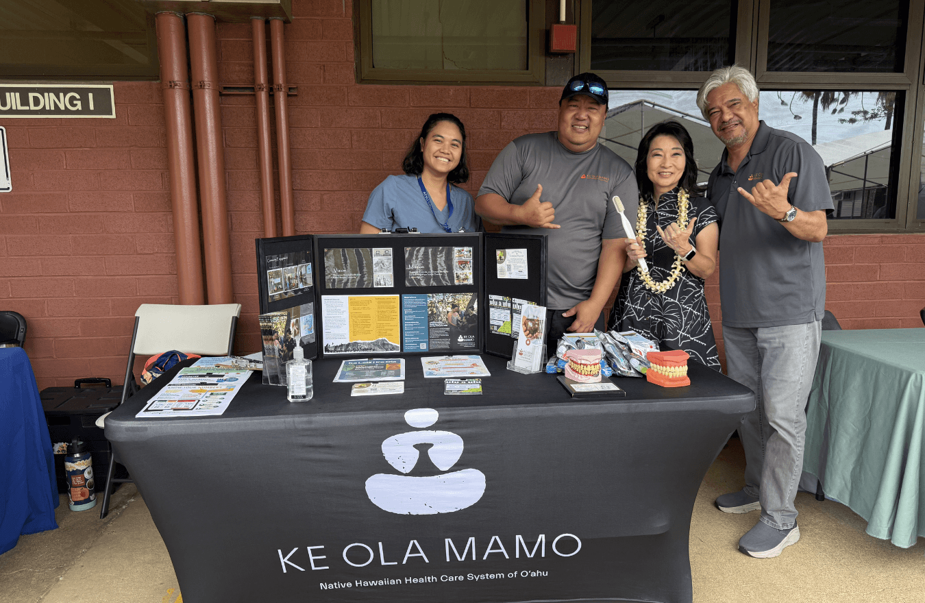 Lt. Gov. Sylvia Luke and group smiling and holding up shakas for a photo in back of a table with a presentation board on it. 