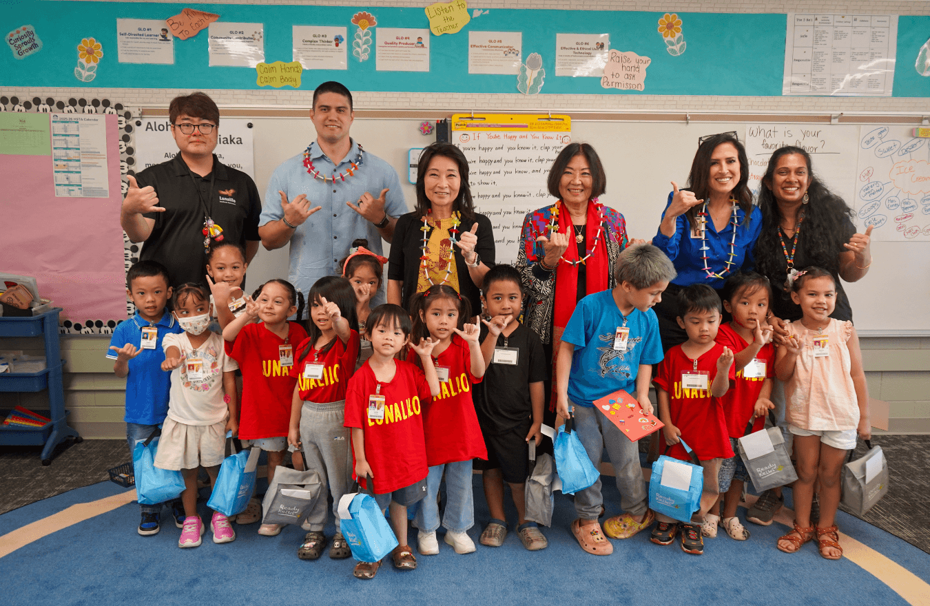Lt. Gov. Sylvia Luke, legislators, teachers, and pre-k students holding lunch bags smiling and holding up shakas in a Ready Keiki preschool classroom in Honolulu, Oʻahu. 