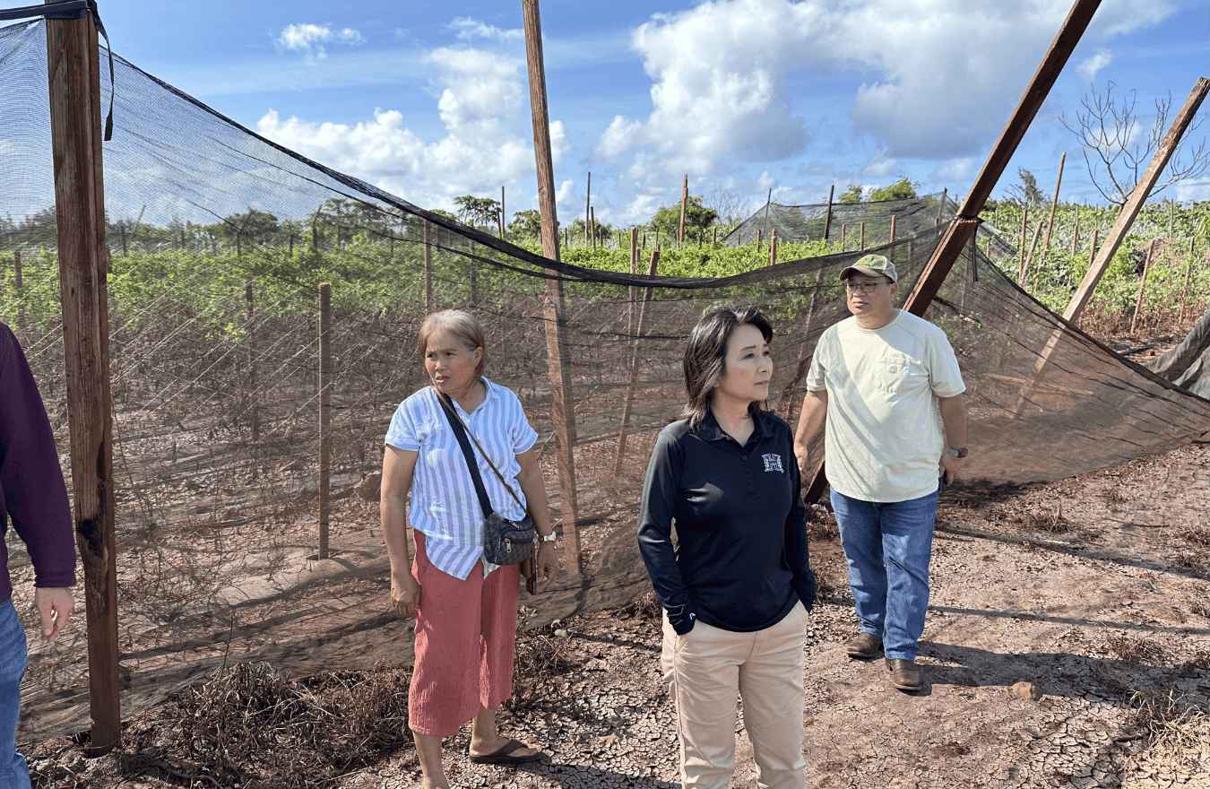 Lt. Gov. Sylvia Luke and two individuals standing on dirt with plants in the background.  