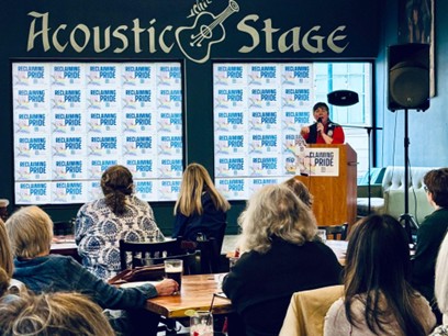 State Rep Betsy Coffia speaking on stage to a crowd of community members at the Reclaiming Pride event. State Rep Betsy Coffia speaking on stage to a crowd of community members at the Reclaiming Pride event.