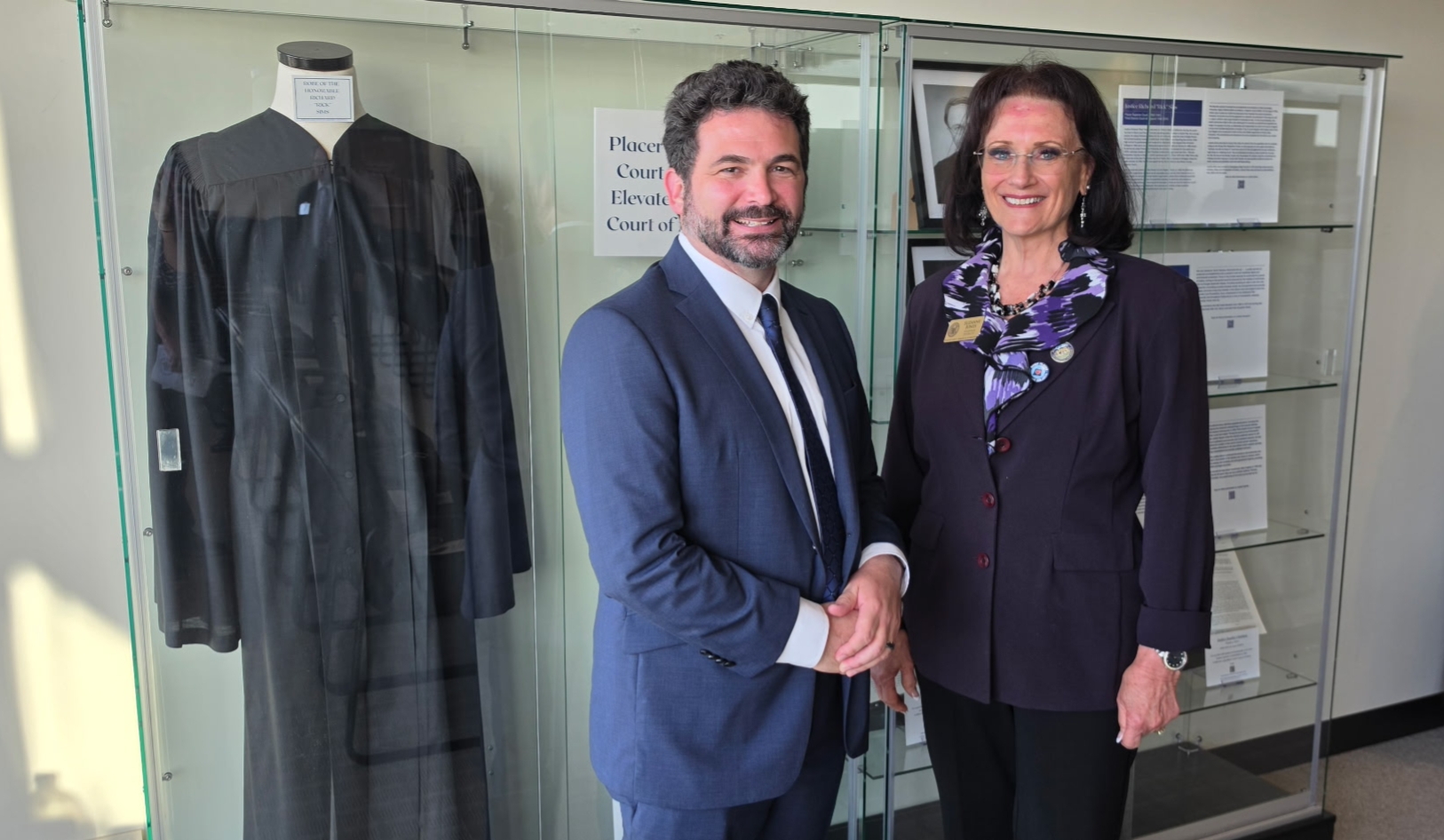 Supervisor Jones standing with a colleague in front of a display case with a judge's robe on display