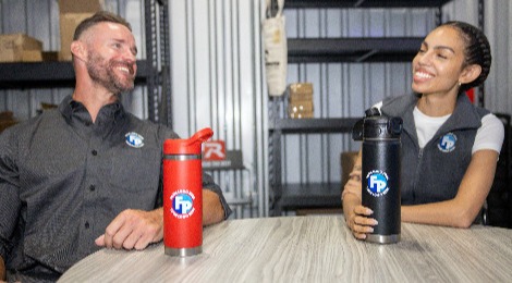 A man and a woman wearing Fully Promoted branded apparel with Fully Promoted branded drinkware
