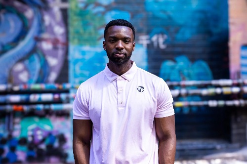 A man wearing a pink polo with the black Fully Promoted circle logo.