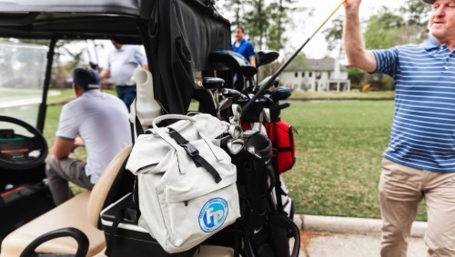 A white branded fully promoted backpack on a golf cart.