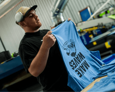 Worker folding a light blue screen printed Tshirt.