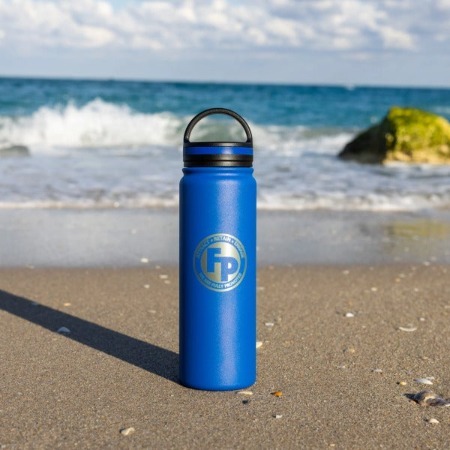 A blue fully promoted branded drinkware placed on the sand in the beach.