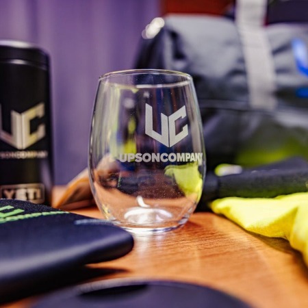 A branded glass with a white logo placed on a table.