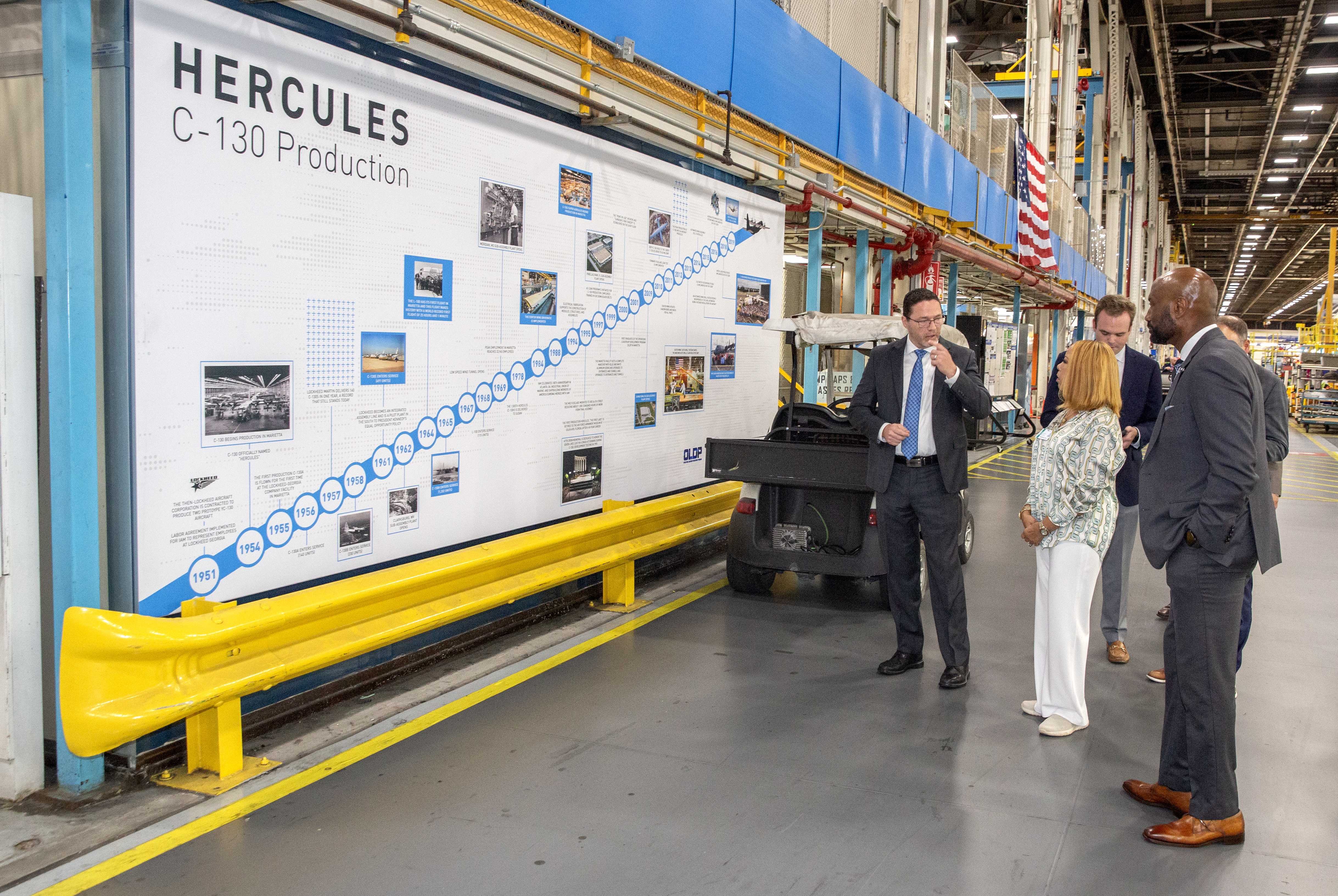 Photo of Rep. McBath standing in front of a large graphic detailing information on C-130 production at Lockheed Martin in Marietta.