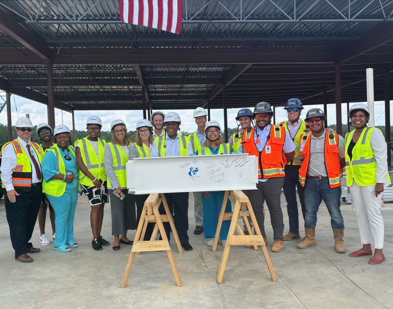 Photo of Rep. McBath standing in front of a steel beam with representatives from Grady Hospital and construction workers.