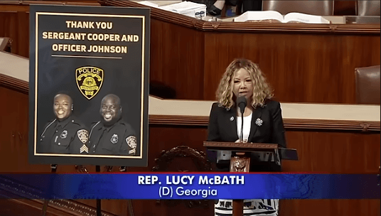 Rep. McBath speaking from the House floor beside a poster that reads "Thank you Sergeant Cooper and Officer Johnson."