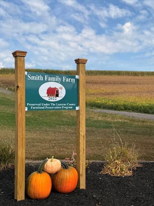 A picture of a sign that says "Smith Family Farm" with pumpkins underneath.