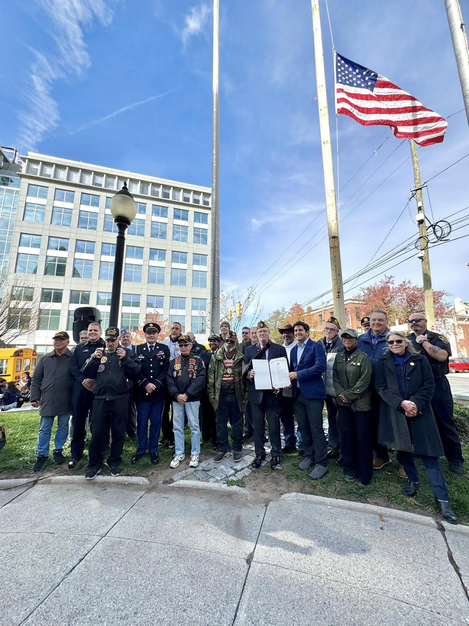 image of veterans standing under the county American Flag at the Veterans Day flag raising ceremony.