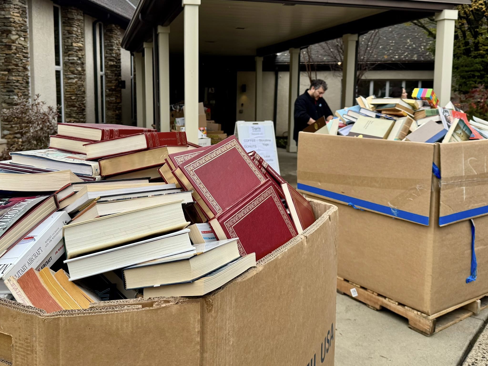 A photo of oversized brown cardboard boxes overflowing with book donations.