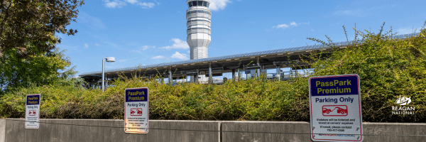 View of Reagan National Airport control tower and terminal behind parking signs for PassPark Premium.