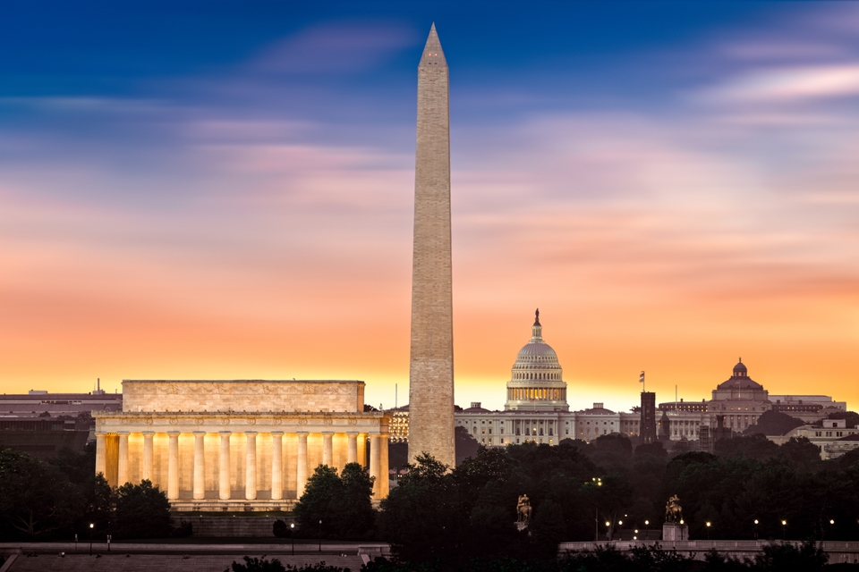 View of the Washington Monument and the United States Capitol building at dusk, with a vibrant sunset in the background.