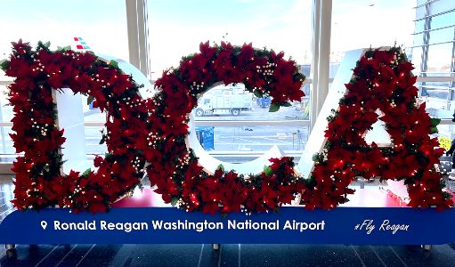 Decorative floral arrangement spelling "DCA" in front of a window at Ronald Reagan Washington National Airport, with an airplane visible outside.