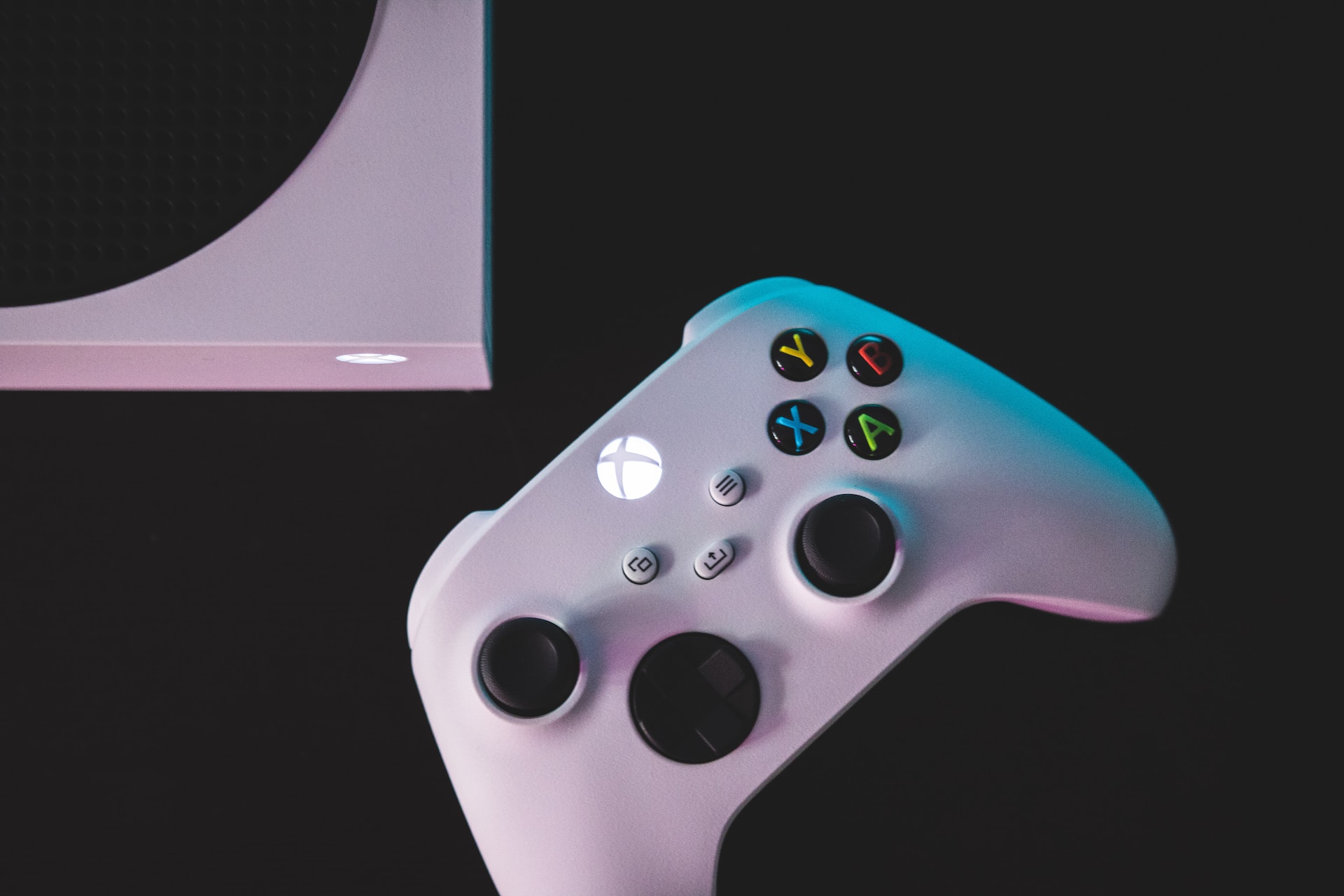 Siyah bir masanın üstünde beyaz Xbox Series S oyun konsolu ve Xbox oyun kontrolcüsü duruyor.