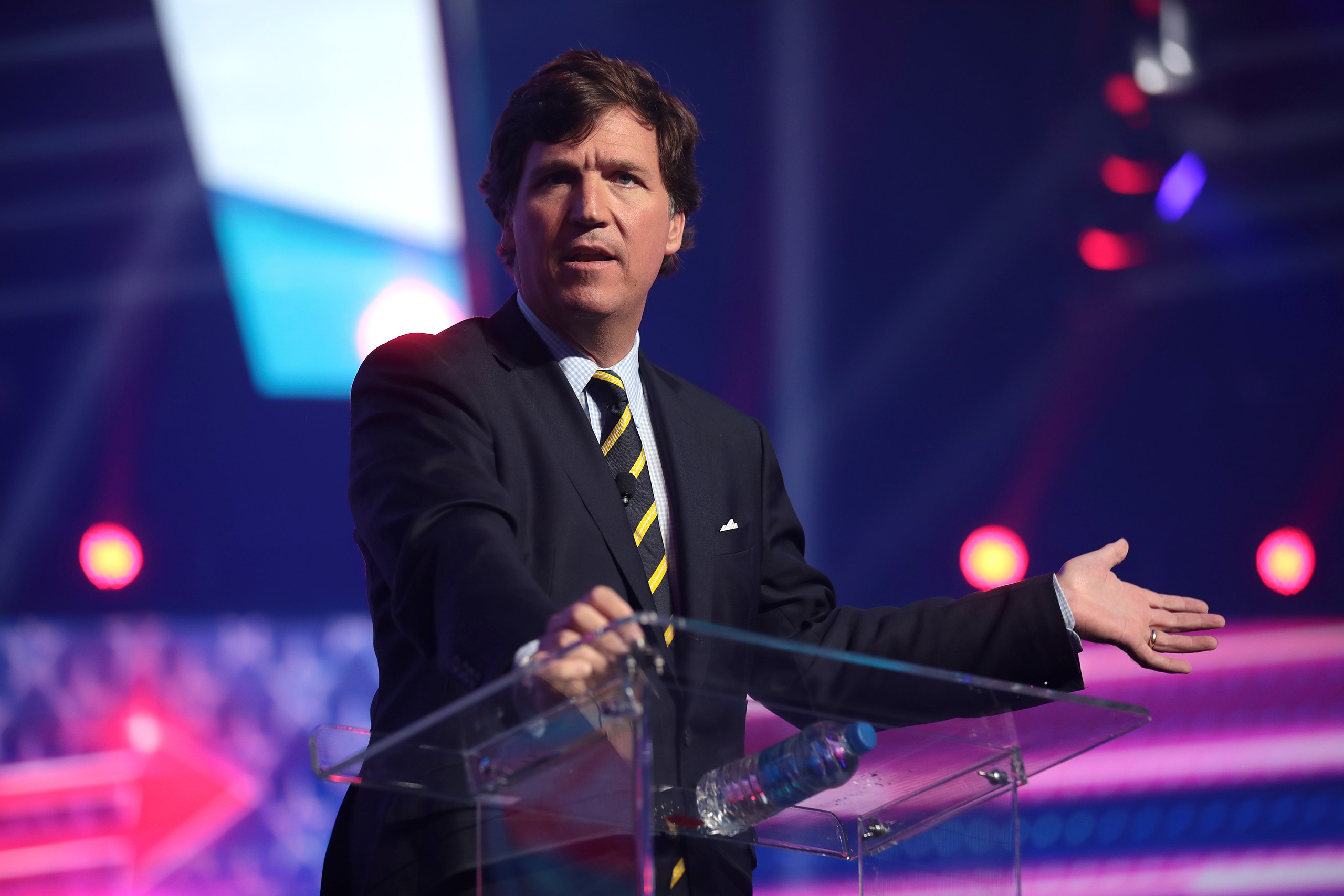 Tucker Carlson'ın bir etkinlikte kürsüde konuşurken çekilmiş bir fotoğrafı.