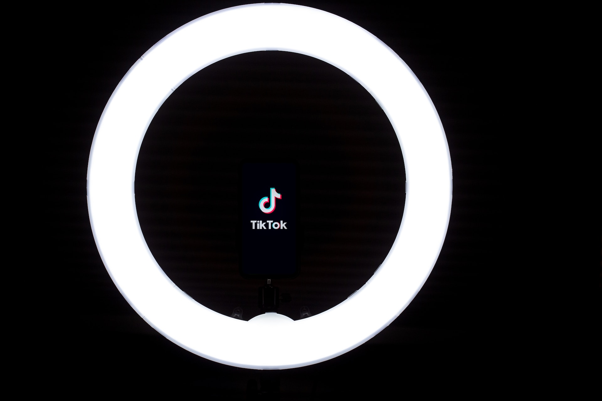 Karanlık bir odanın içerisinde yanan ring light'ın ortasında TikTok logosu görülüyor.