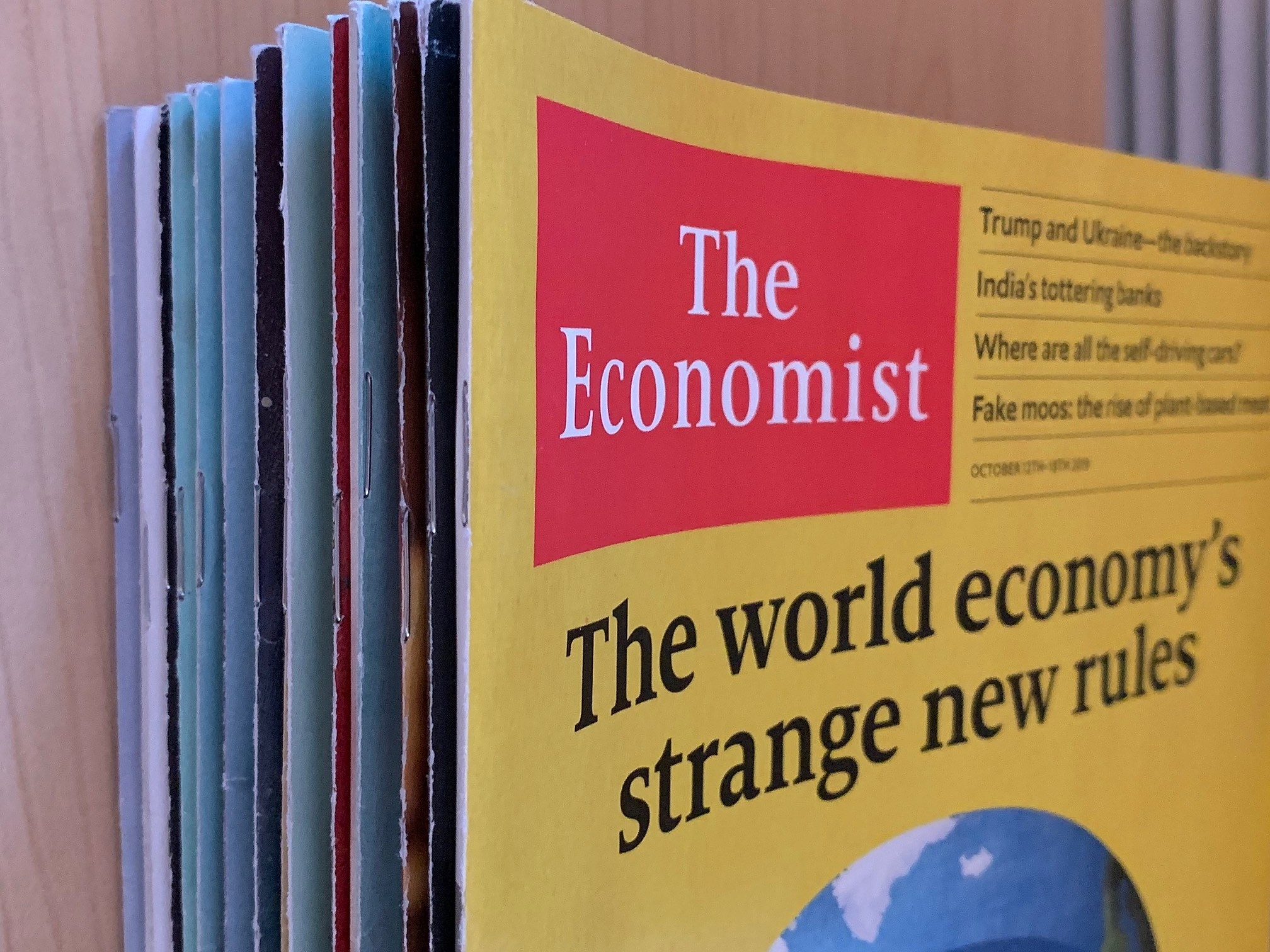 Bir masanın üzerinde üst üste duran Economist dergileri.