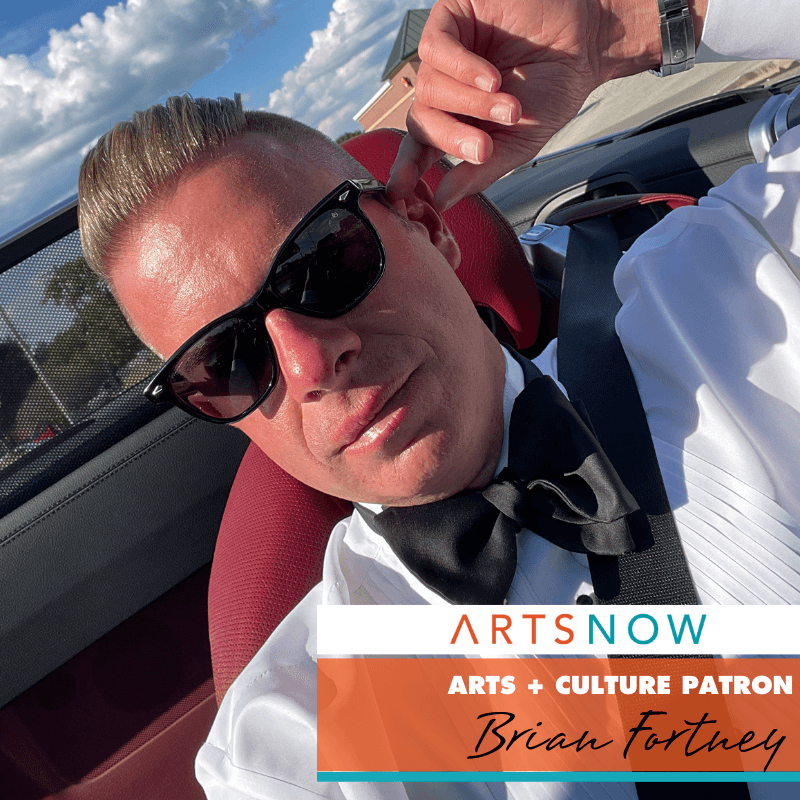 Photo of a man in a car. To the right, is text in a white box with orange and blue text that reads: ArtsNow. Below is text that reads: Arts + Culture Patron: Brian Fortney.