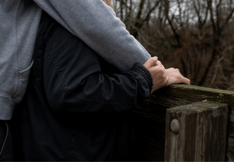 Photo of two arms and hands holding. 