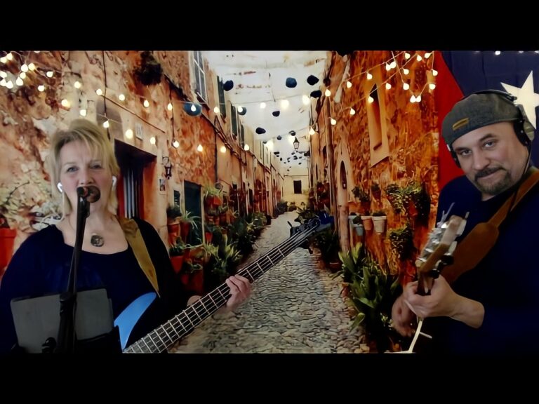 A man and woman performing behind a backdrop of an ally with lights from building to building.