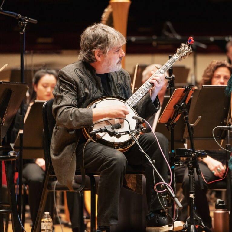 Man playing a banjo with an orchestra.