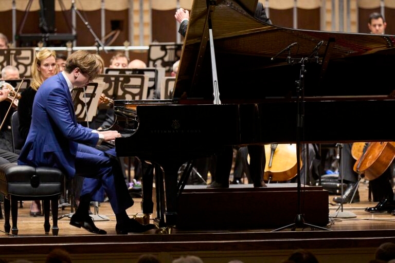 Man in a blue suit playing on the piano. 